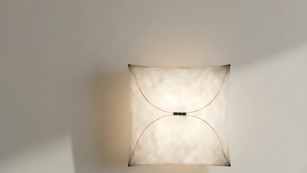 A warm, serene minimalist living room featuring the sculptural Ariette Kite Washi Paper Wall Sconce glowing softly on a textured plaster wall above a wooden table.